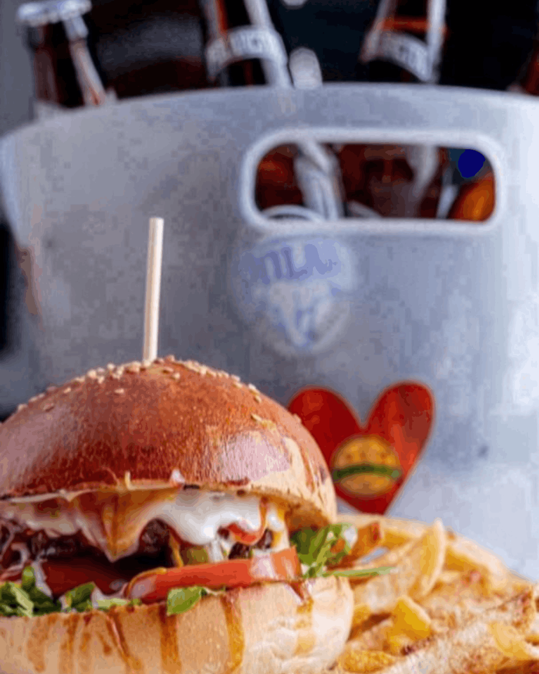Hamburguesa clásica con vegetales acompañada de cervezas frías en En Alturas Café, Mérida.