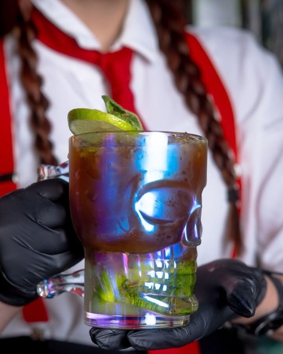 Bartender del equipo de barra sirviendo un coctel en vaso de craneo en En Alturas Cafe, Merida